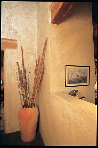 An old-fashioned but efficient woodstove near the kitchen picks up the slack during very cold weather or cloudy days. Surface-bonding mortar gives interior walls a sculptural feel.